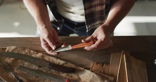 Mittelteil eines kaukasischen männlichen Messermachers in der Werkstatt, Messer in der Hand