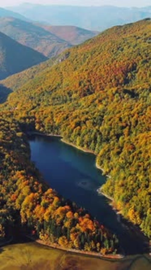 Aerial view of lake surrounded by mountains with autumn trees