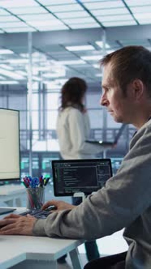 IT Programmer Arriving at Work in Data Center Sitting at PC Desk