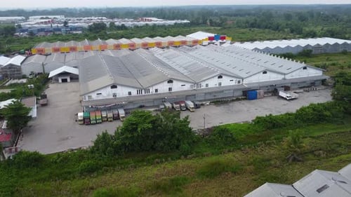 Aerial view of a goods distribution warehouse lined up with goods trucks parked in front of the ware