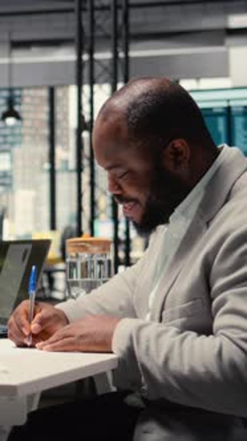 Man Writes at Desk in Modern Office