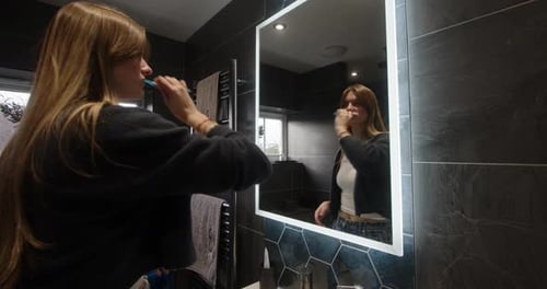 Woman Brushing Teeth in Modern Bathroom