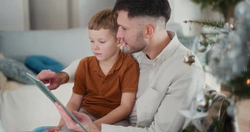 Un niño y su padre miran las Fotos de un Álbum