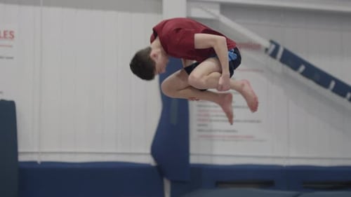 Young man slow motion flips side angle gym