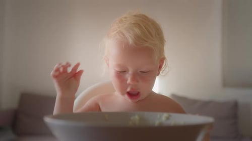 Child Eats with Hands in High Chair