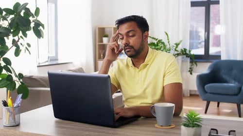Hombre indio preocupado que trabaja desde su oficina en casa en una computadora portátil pensando en un problema