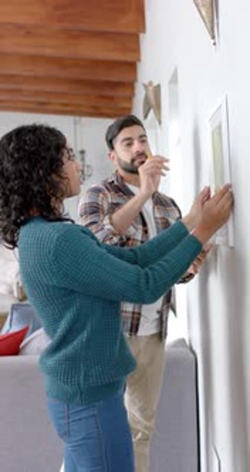 Vertical video of couple taking measurements on wall at home, slow motion