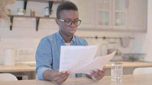 Young Adult Reading Papers at Kitchen Table