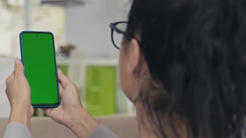 Woman Holding Smartphone with Green Chroma Key Screen in front of Eyes
