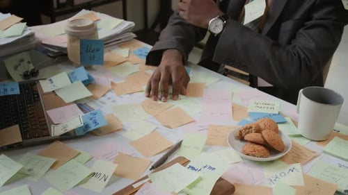 Busy African American Man Working at Office Desk, Littered with Sticky Notes