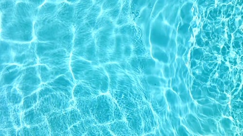 Blaues Wasser im Schwimmbad mit Lichtreflexen in Zeitlupe