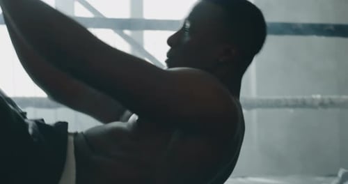 Cinematic shot of a professional young muscular shirtless african man is practicing shadow boxing