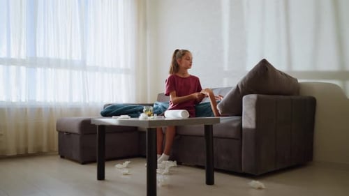 Une sœur remet un thermomètre à un frère fiévreux avec des tissus jonchés et des ombres sur le mur