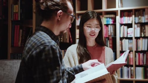 Young Man and Woman Discussing Book in Public Library