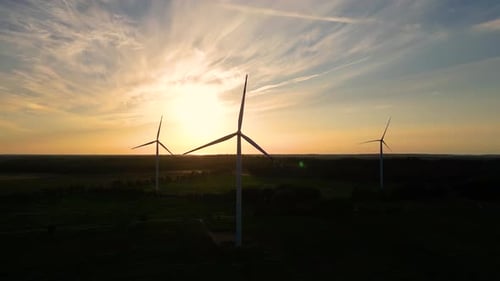 Große Windturbinen mit Rotorblättern im Feld, Luftbild, leuchtend orange, Sonnenuntergang, blauer Himmel, Windpark, Zeitlupe