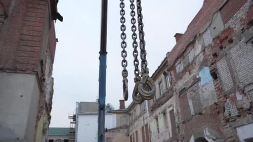 Hooks Hang Motionless Against Backdrop of Fragile Bricks