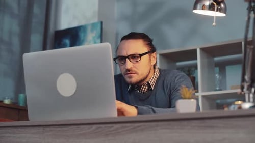 Un professionnel concentré qui travaille assidûment sur un ordinateur portable dans un environnement de bureau moderne