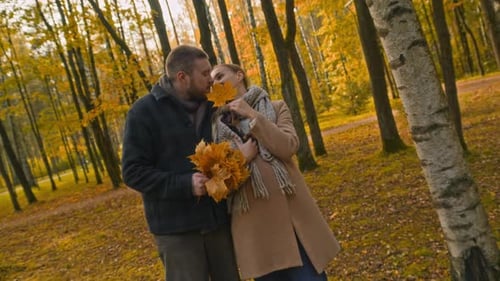 Romantic Couple with Bouquet of Autumn Leaves and Dog in Forest Park