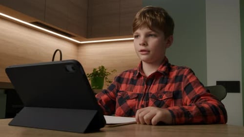 Boy Uses Tablet at Table for Education