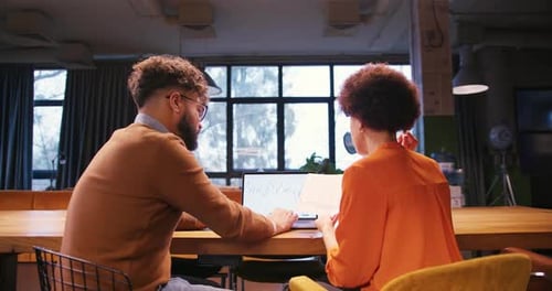 Professional Two Colleagues Analyzing Documents Using Laptop Working in Modern Office