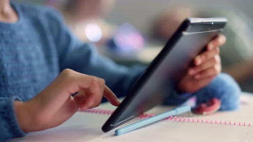 Female Student Hand Using Digital Tablet at Desk in School Classroom. Closeup