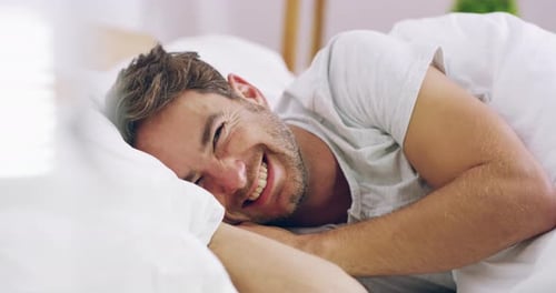 Man Smiling Lying in Bed with White Sheets