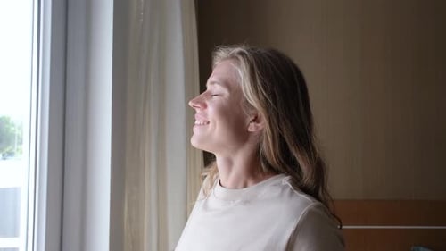 Woman Stretching and Smiling in Sunny Bedroom