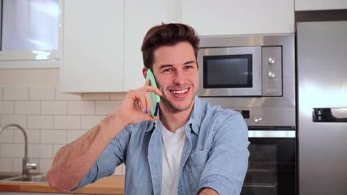 Young Man Talking on Smartphone in Kitchen