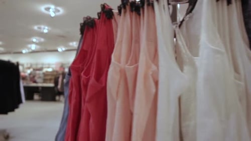 La caméra se déplace vers un cintre à vêtements rond avec des robes aux couleurs vives