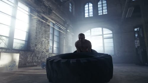 Ein
starker muskulöser Mann hebt oder dreht den Reifen im Rahmen seines Bodybuilding-/Cross-Fitnesstrainings um. Er ist Cov