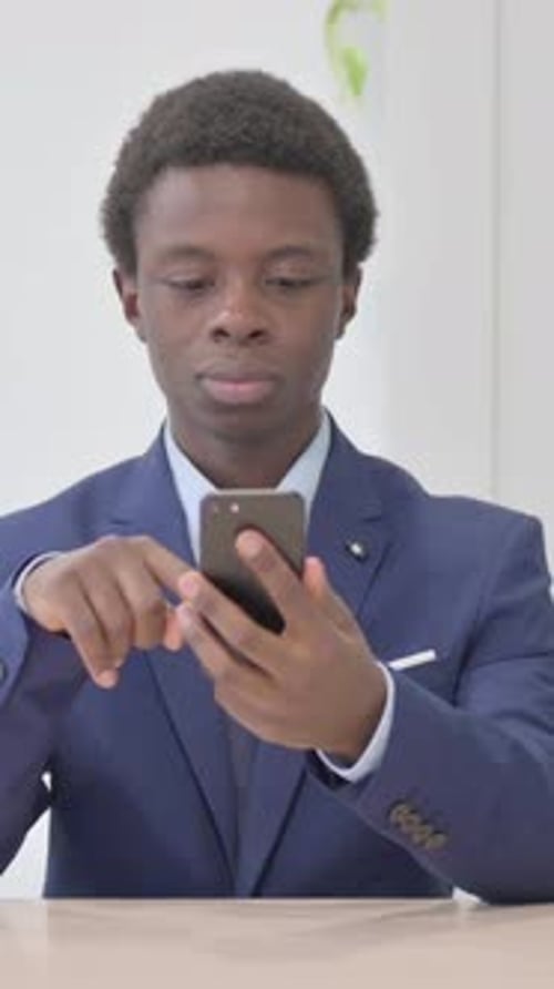 Young Man in Suit Using Smartphone Celebrates Success