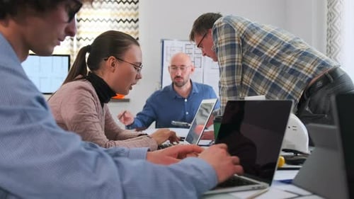 Team Brainstorming Session Caucasian Team Engaged in Lively Laptopbased Discussion Group of