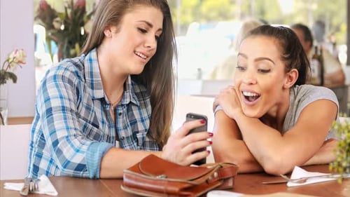 Two young women looking at a smartphone, smiling