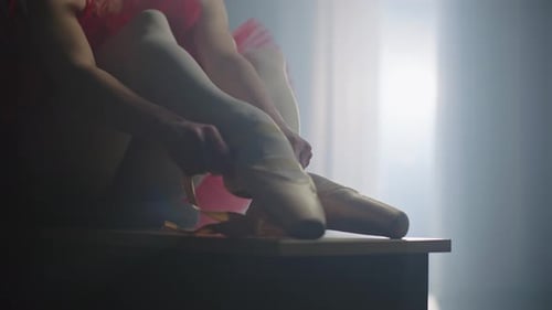 Ballet Dancer Tying Ballet Shoes with Red Tutu