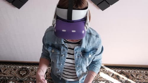 Jovem mulher em um fone de ouvido de realidade virtual joga um jogo em casa