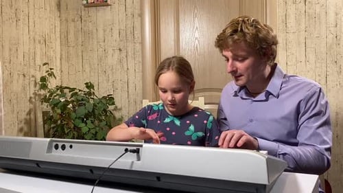 Girl Learning Piano with Curly Haired Teacher