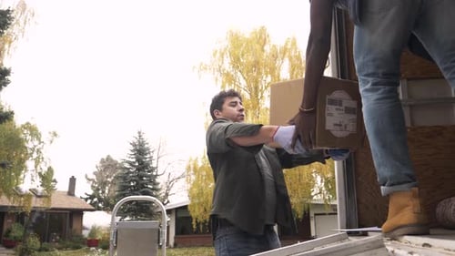 Men unloading cardboard boxes from a moving truck