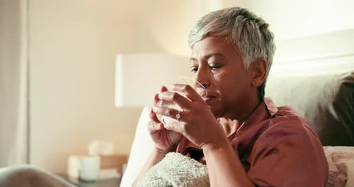 Woman Takes Pill and Drinks Water in Bed