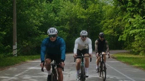 Rennführer in Schutzhelmen fahren mit dem Fahrrad auf der Asphaltstraße