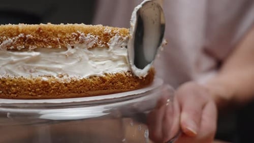 Der Konditor dreht den Kuchen und verteilt die Sahne zwischen den Biskuitschichten gleichmäßig. Langsamer Lauf