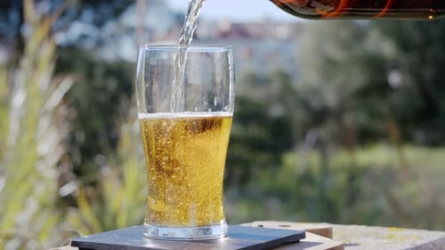 Pouring Refreshing Beer into a Glass Outdoors