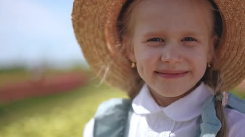 A Charming Child Adorned with a Straw Hat Joyfully Playing in a Vibrant Flower Field