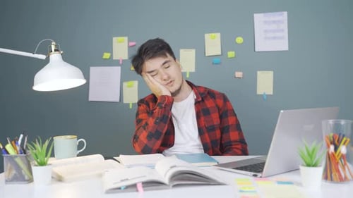 Tired Student At Desk Struggles to Stay Awake