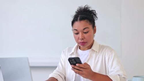Woman using laptop computer and mobile phone indoors