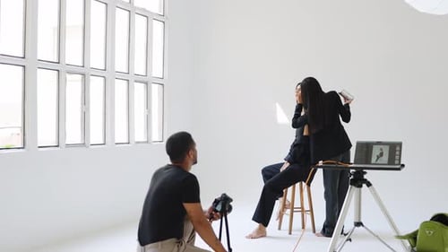 Photographer Guiding Model Posing in Slow Motion in White Studio