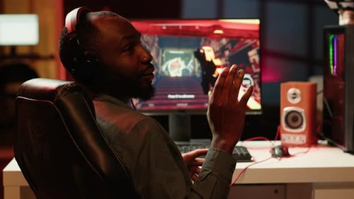 Gamer gesturing in front of computer with headset