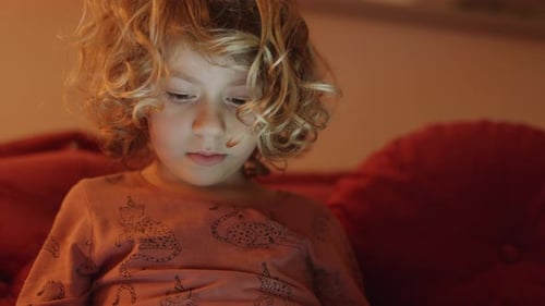 Small Girl Plays or Watches a Tablet Computer