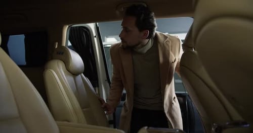 A Man Examines with Interest the Features of the Interior of a New Car in a Car Dealership