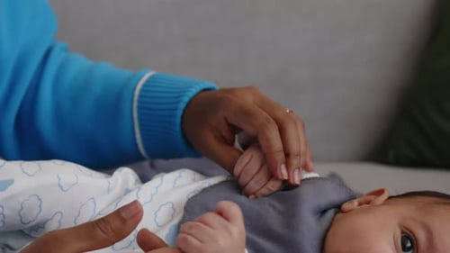Parent Gently Holding Newborn Baby's Hand at Home