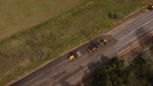 Road roller in rural road construction, South America. Aerial top-down orbiting